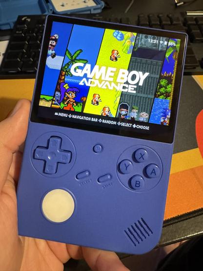 Violetti retro käsikonsoli kädessä. Konsolissa on valkoinen 3d-tulostettu kiekko tattiohjaimen tilalla.