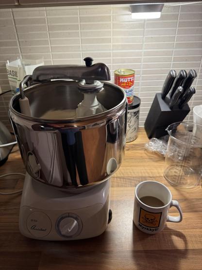 Taikina pyörimässä yleiskoneessa ja vieressä kahvikuppi.