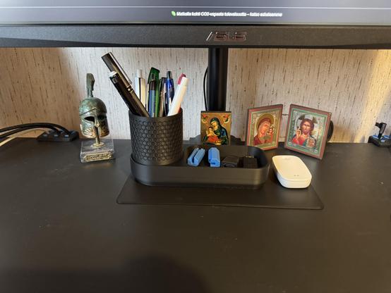 Työpöydälle laitettu 3D-tulostetun peitelevyn päälle kynäteline ja ikoneita sekä kreikkalaisteemainen pieni kypärä patsas.