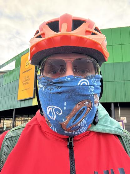 Ukko pyöräilykypärä, aurinkolasit ja suoja naamalla.