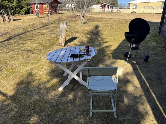 Pöytä ja tuoli ulkona pihalla, grillien ja kevätsää.