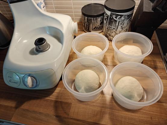 4kpl pizzapalloja muoviastaissa taikinakoneen vieressä.