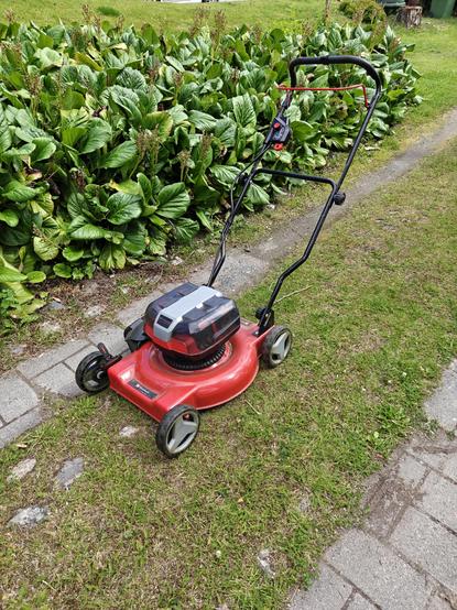 Puna-musta ruohonleikkuri nurmikolla.
