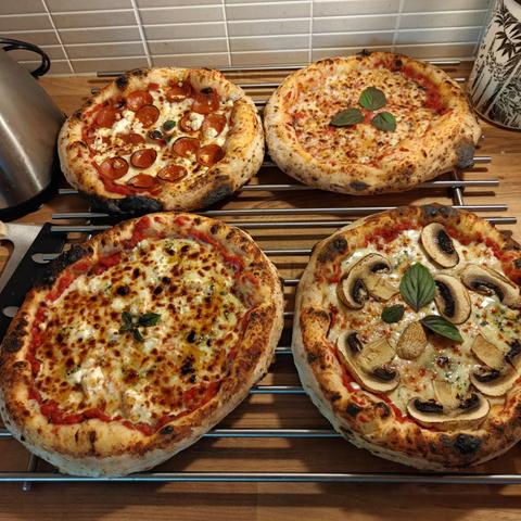 Neljä erilaista pizzaa pöydällä.
