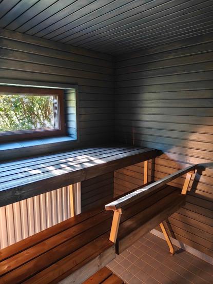Sauna jossa on tummemmat lauteet sekä lattia ja katto.